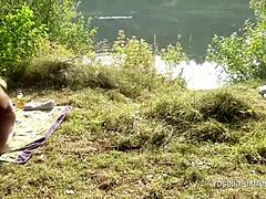 Zrela ženska požira spermo in piša v javnosti ob plavalnem jezeru